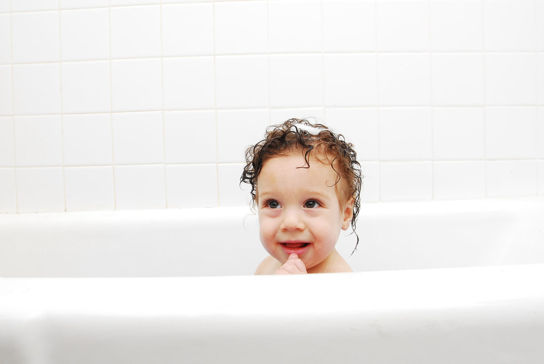 Sensitive skin kid in the bath tub with wet hair and gentle soap